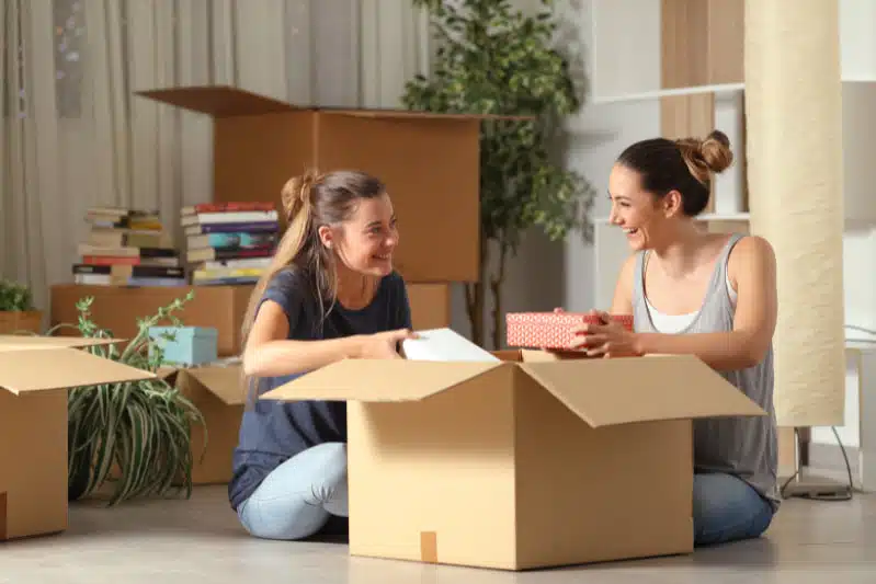 Twee jonge vrouwen halen samen spullen uit een verhuisdoos